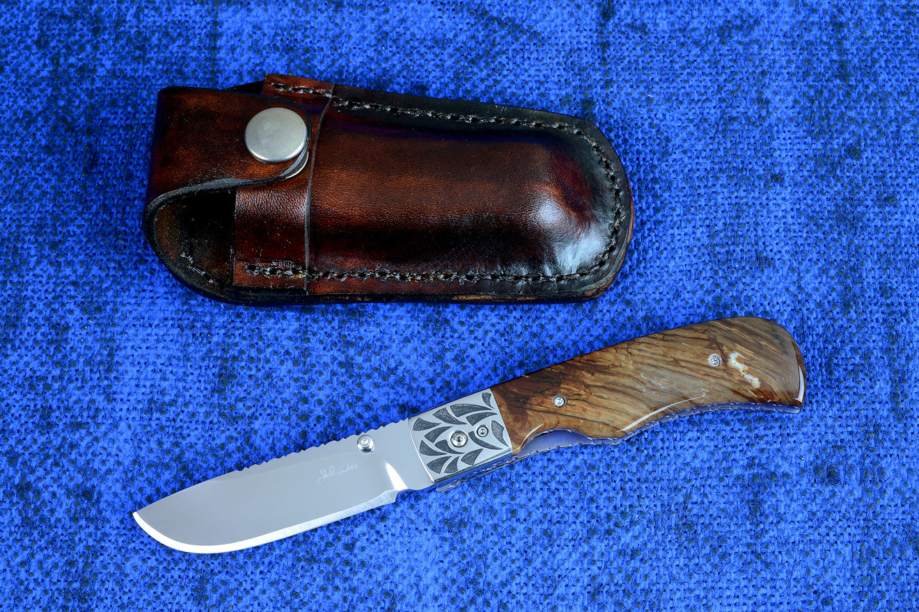 "Sadr" linerlock folding knife, obverse side view in 440c high chromium cryogenically treated stainless steel blade, hand-engraved 304 stainless steel bolsters, anodized 6AL4V titanium liners, Biggs Jasper Gemstone handle scales, leather pouch sheath with stainless steel snap