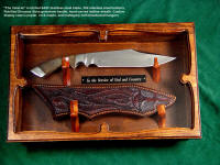 "The Veteran" in display case of poplar with mahogany hinges, hangers of bloodwood signifying sacrifice. Knife has petrified dinosaur bone gemstone handle, etched stainless steel blade, hand-cared leather sheath