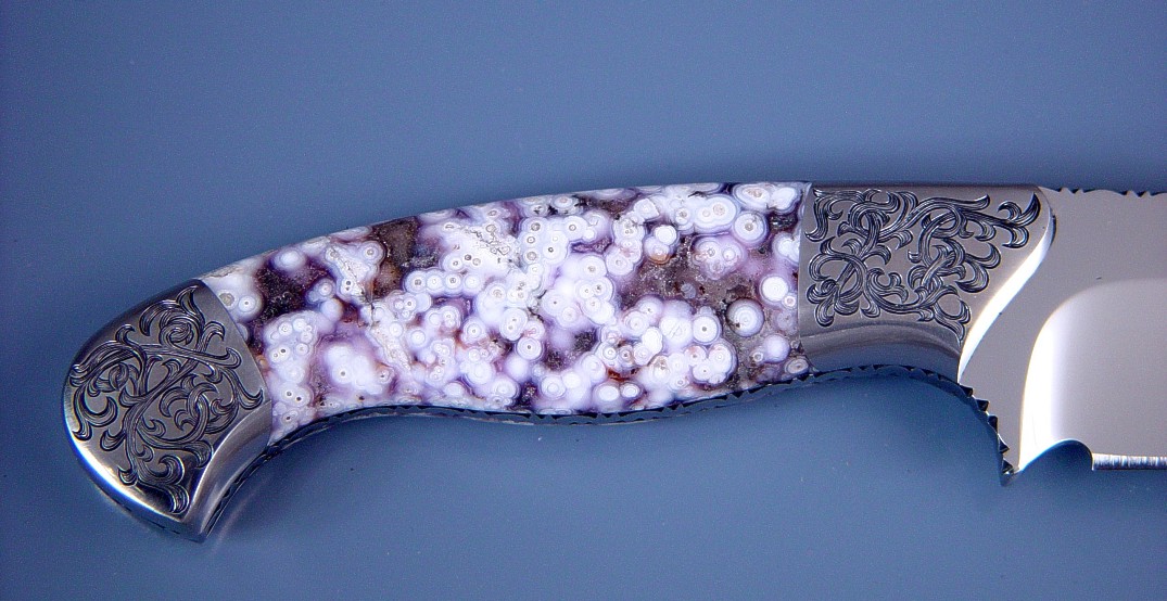 "Alegre" Obverse side view. 440C high chromium stainless steel blade, fully fileworked, mirror finished, hand-engraved 304 stainless steel bolsters, Orbicular Amethyst Gemstone handle, Frog skin inlaid in hand-carved leather sheath