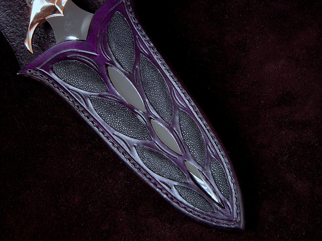 "Amethistine" dagger, obverse side view in 440C high chromium stainless steel blade, diffusion welded copper, nickel silver fittings, sterling silver gallery wire wrap and accents, Amethyst crystal gemstone pommel, hand-carved leather sheath inlaid with black rayskin