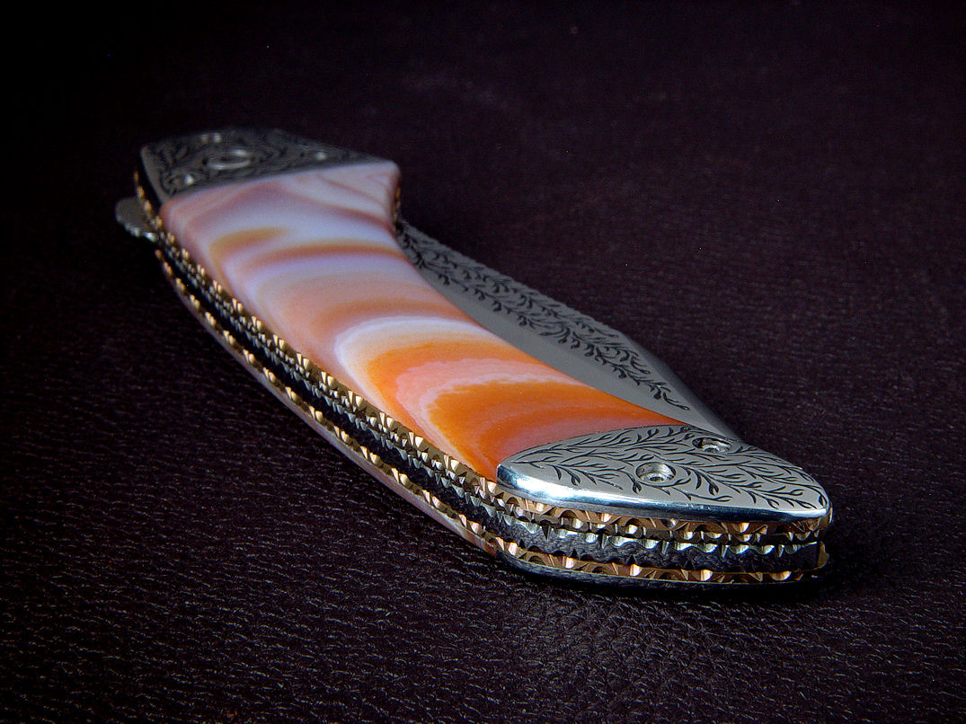 "Procyon" reverse side view in hand-engraved 440C high chromium stainless steel blade, hand-engraved 304 stainless steel bolsters, anodized 6AL4V titanium liners and lock, polished Brazilian Agate gemstone handle, breccia marble case