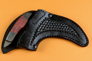 "Chela" karambit knife,  post-lock sheathed view, in T4 cryogenically treated 440C high chromium martensitic stainless steel blade, 304 stainless steel bolsters, red and black tortoiseshell G10 composite handle, leather sheath with stainless steel and nylon