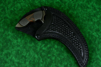 "Drepan" tactical karambit knife, sheathed view in T4 cryogenically treated 440C high chromium martensitic stainless steel blade, 304 stainles steel bolsters, orange/black G10 fiberglass epoxy composite laminate, sheath in leather shoulder, hand-tooled, nylon stitching, stainless steel reinforcement