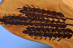 "Sasserides and Courgette" fine handmade  bread knife set, detail of laser engraving of wheat stalks in cherry hardwood