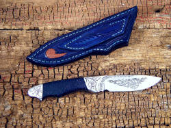 "Thuban" reverse side view. Knife is fully engraved, on grind, flats, and bolsters, all stainless steel. Sheath back has lizard skin inlay.
