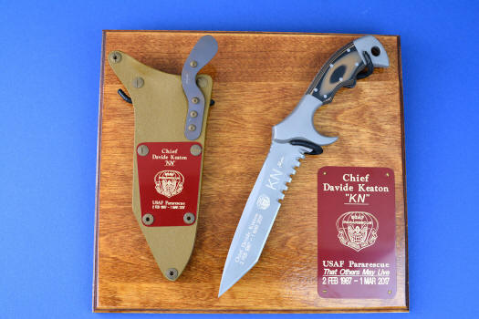 "Uvhash" Custom Commemorative Pararescue Knife, obverse side view, in 440C high chromium stainless steel blade, 304 stainless steel bolsters, coyote/black G10 handle, hybrid tension lock kydex, anodized aluminum sheath, plaque in ash, engraved maroon lacquered brass